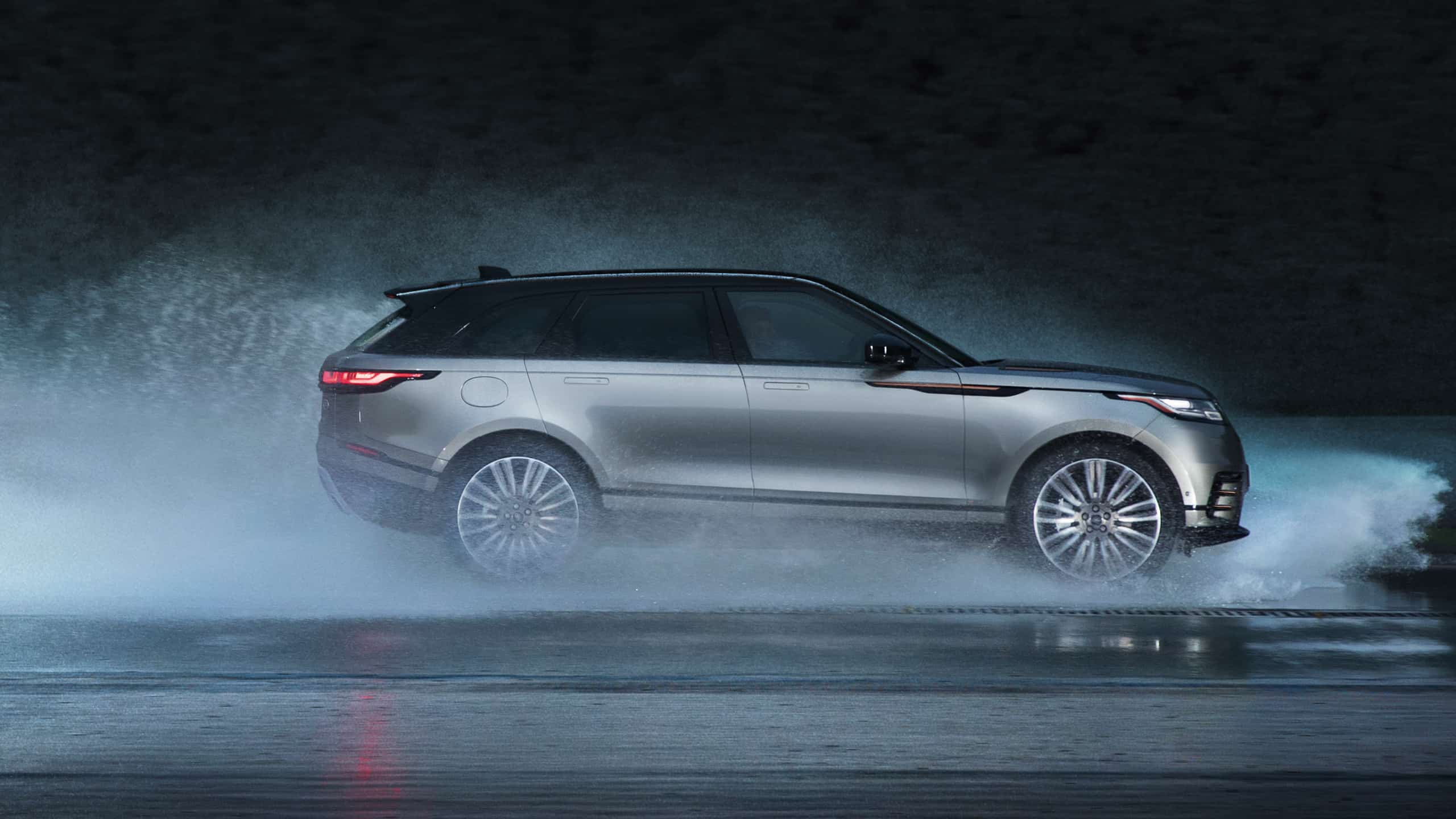 Velar driving quickly through water on road