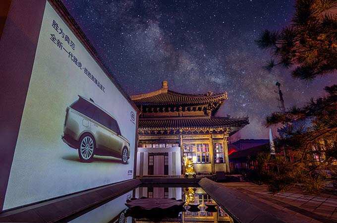 A billboard with the New Range Rover advertised on it next to a Chinese building