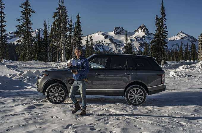 Man standing in front of a land rover vehicle in snowy scenery