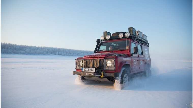 Old model of Land Rover Defender driving in snow