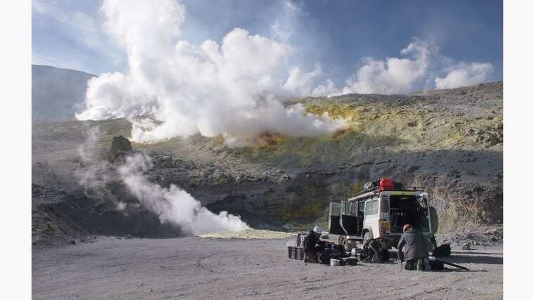 Campers in mountain landscape next to a Land Rover Defender