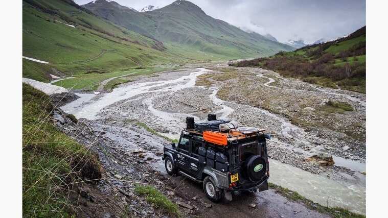 Land Rover Defender driving in mountain landscape camping