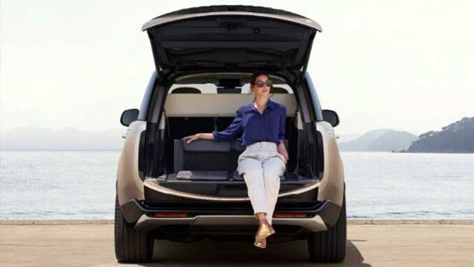 An individual seated on a land Rover vehicle's tailgate