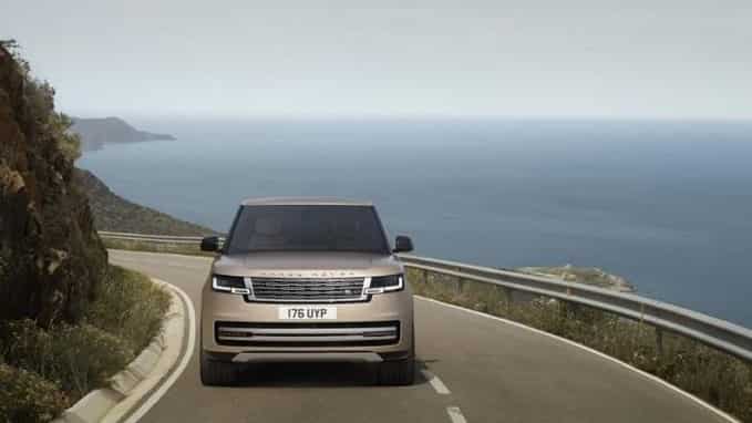 New Range Rover driving on a road next to the sea