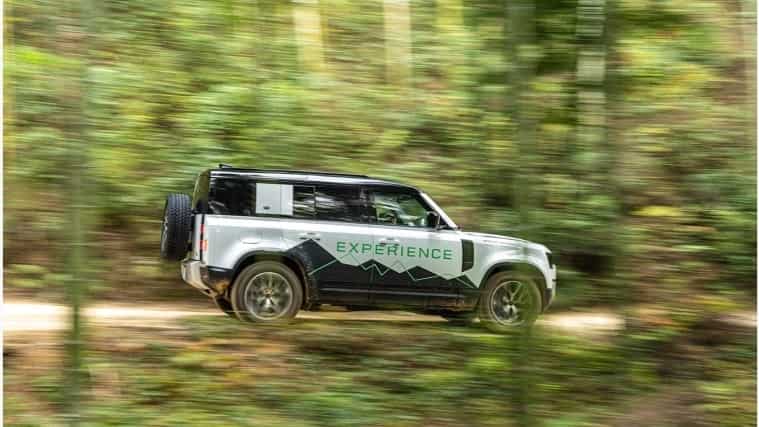 Land Rover Defender 110 driving through forest