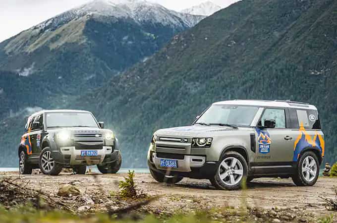 Land Rover Defender vehicles parked in mountain landscape