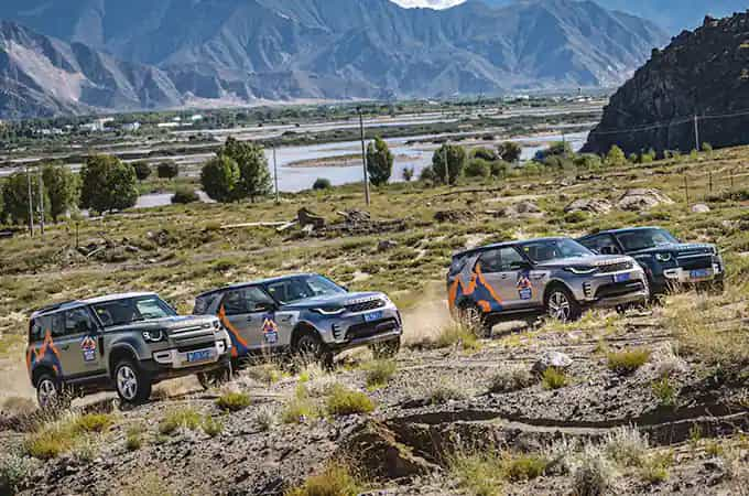 Land Rover Defender and Discovery vehicles driving up hill