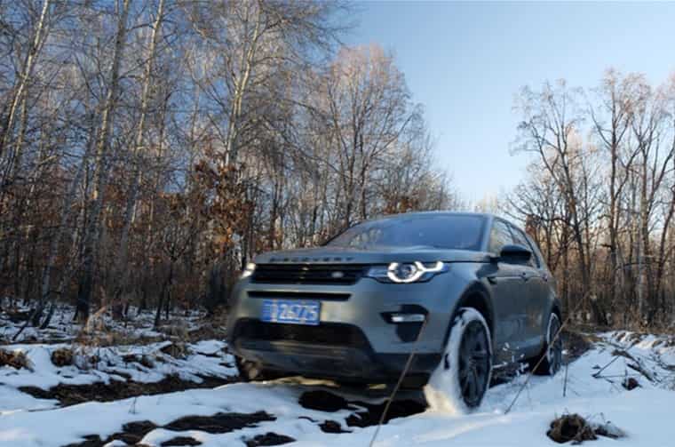 Land Rover Discovery driving through snowy forest
