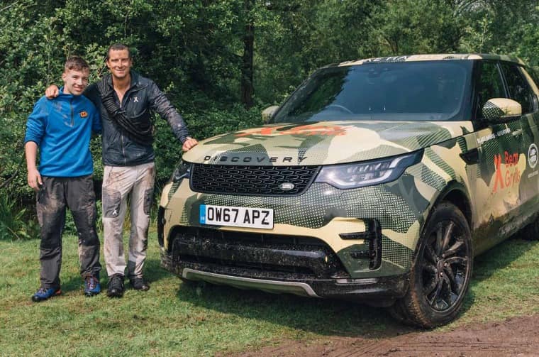 Bear Grylls and boy next to Land Rover Discovery
