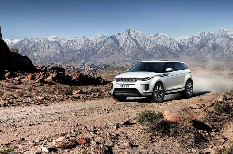 Range Rover Evoque driving on dirt road in mountain landscape