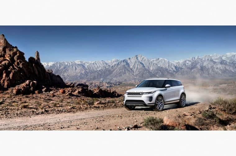 Land Rover Evoque driving on dirt road in mountain landscape