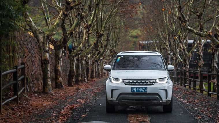 Land Rover Discovery in white driving on country road