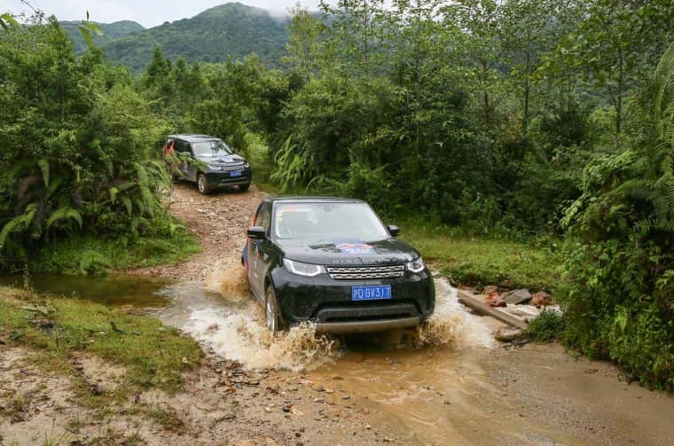 Land Rover Discovery driving through water on mud road