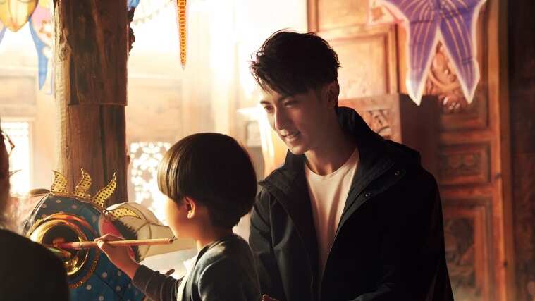 Person looking at child as child paints a mask
